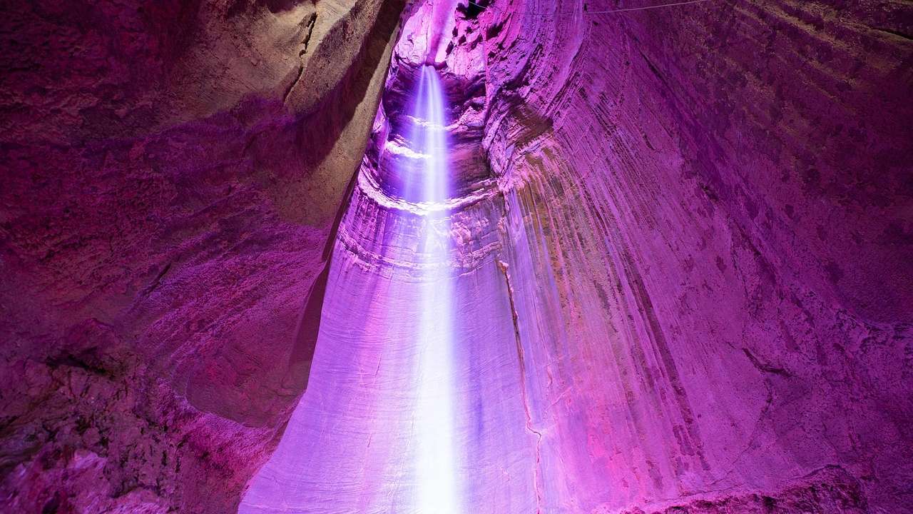 A waterfall flowing into a purple underground cave