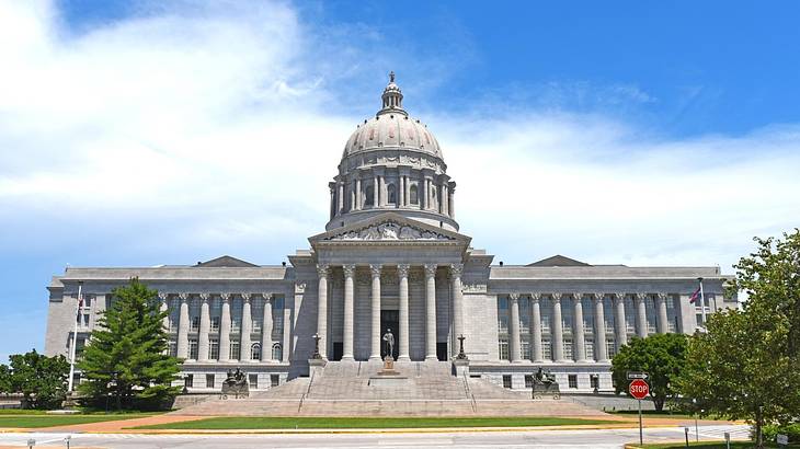 A neoclassical capitol building with a dome against a partly cloudy sky