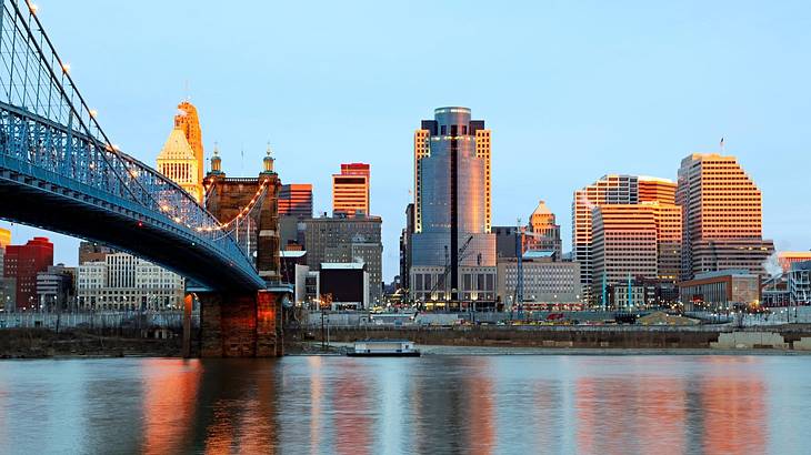 A river with a bridge over it and a skyline on the banks as the sun sets