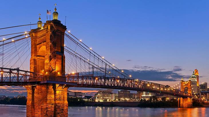 A suspension bridge over the water illuminated at night