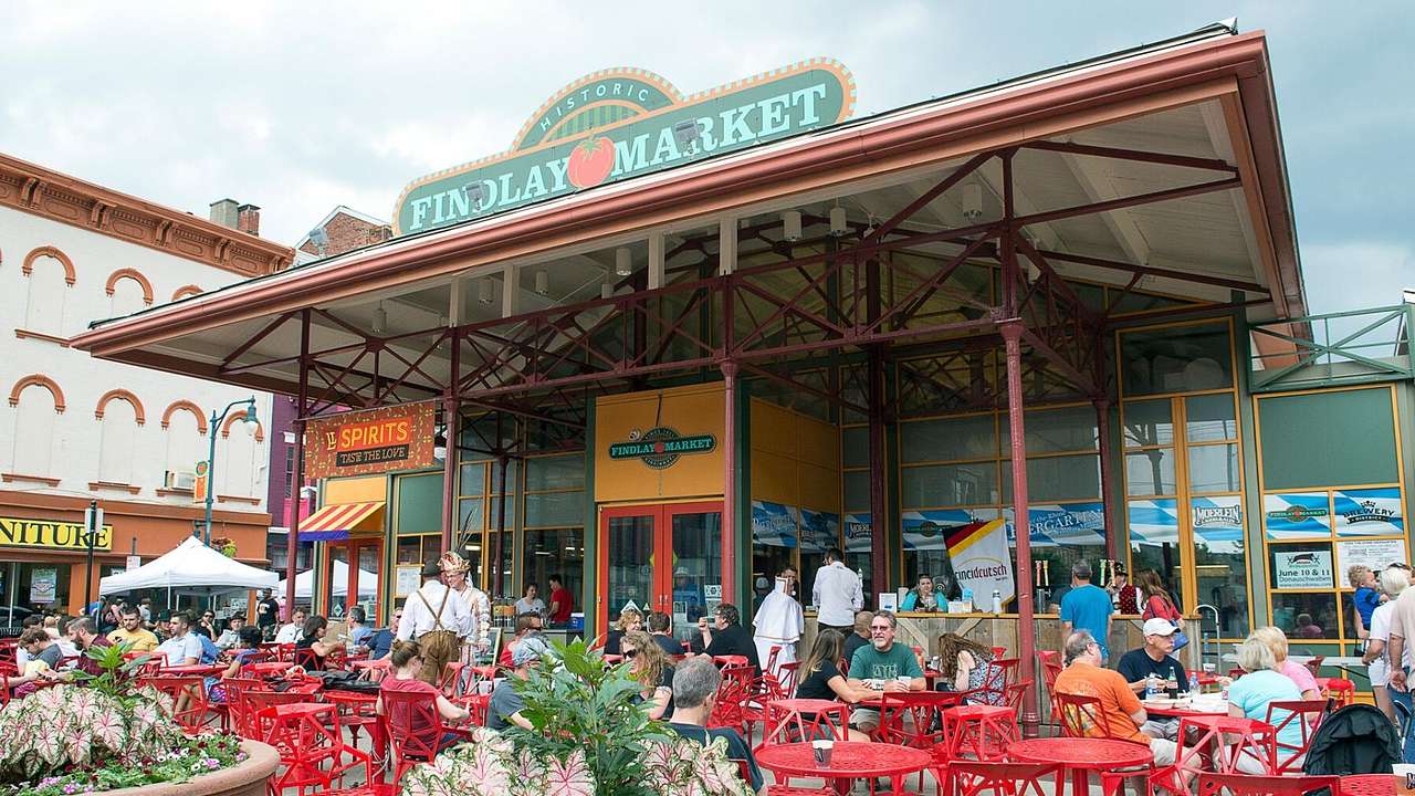 People sitting on a patio in front of a building with a "Findlay Market" sign
