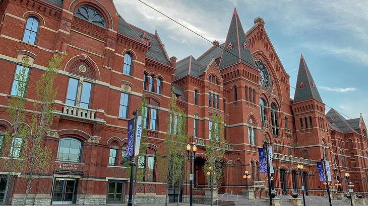 A large brown brick building with flags and light posts in front