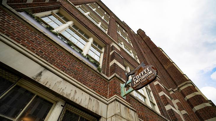 A dark brown building with a sign on the side "Coffee Emporium Really Good Coffee"