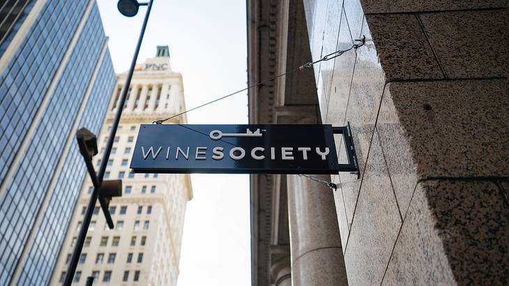 An image facing the sky with buildings and a black sign ÈWine SocietyÈ