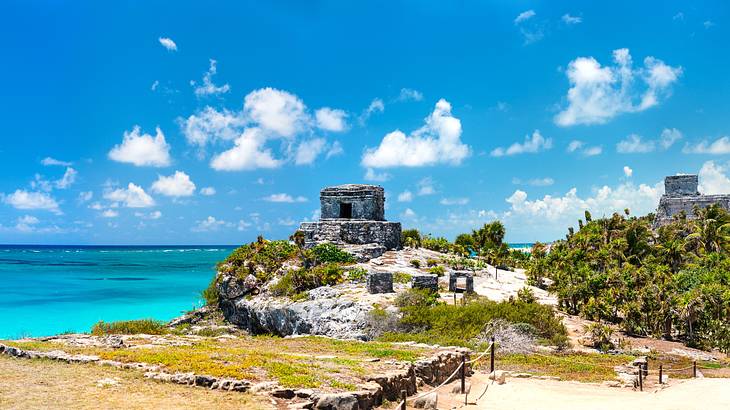 Ancient ruins on top of a rocky hill covered in some grass and trees on the side