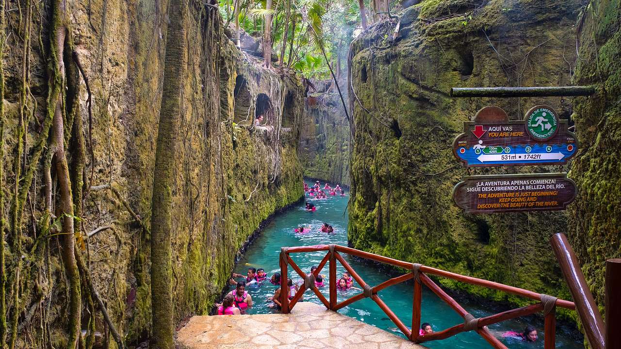 Tourists in life jackets swim in a lazy river that runs through a natural wall