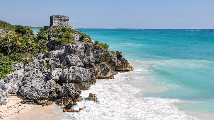 Distant view of old ruins on a rocky cliff, overlooking the blue ocean