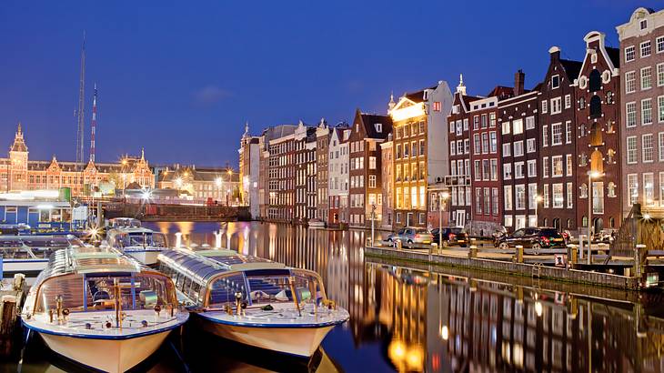 Boats on a canal surrounded by lit buildings at night