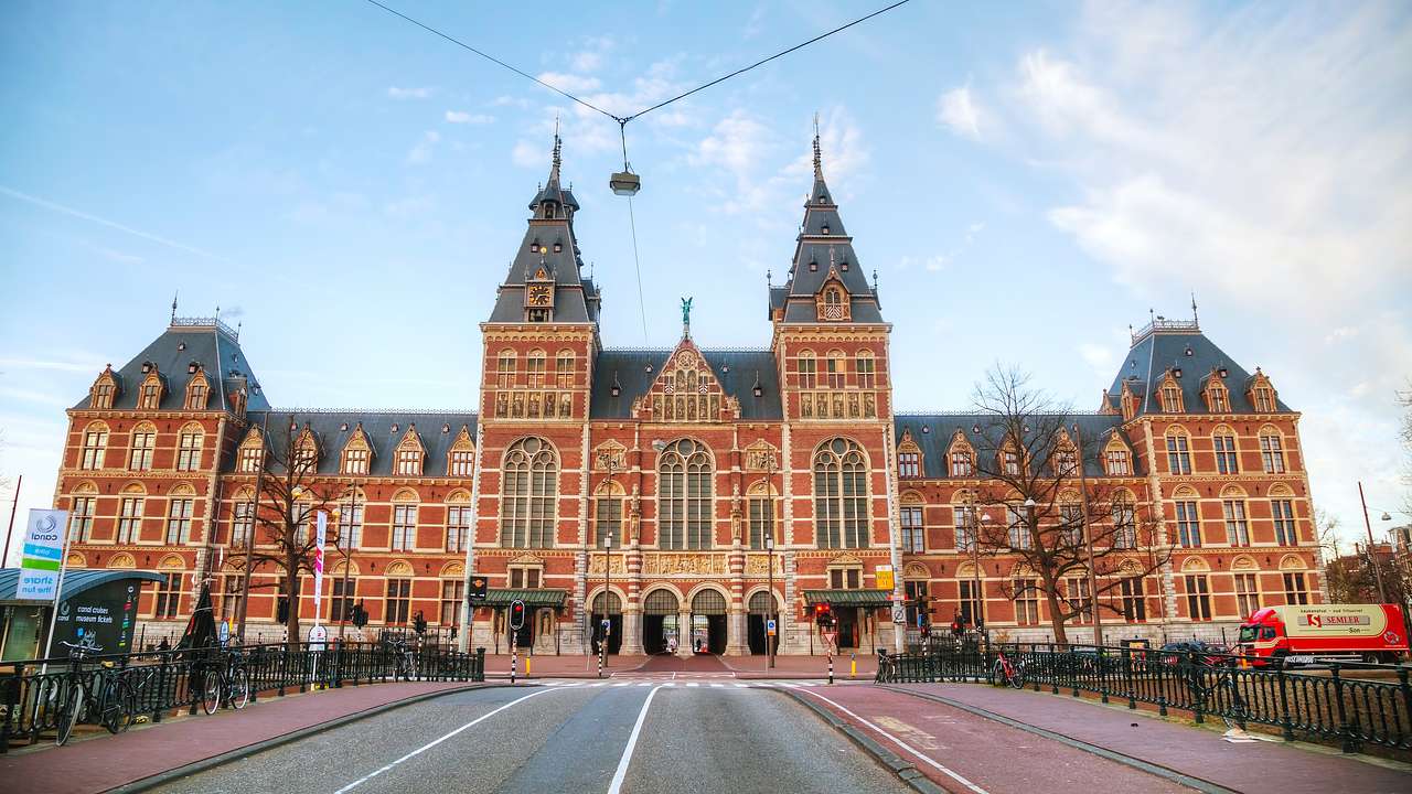 A long brick building with two towers in the middle next to a square