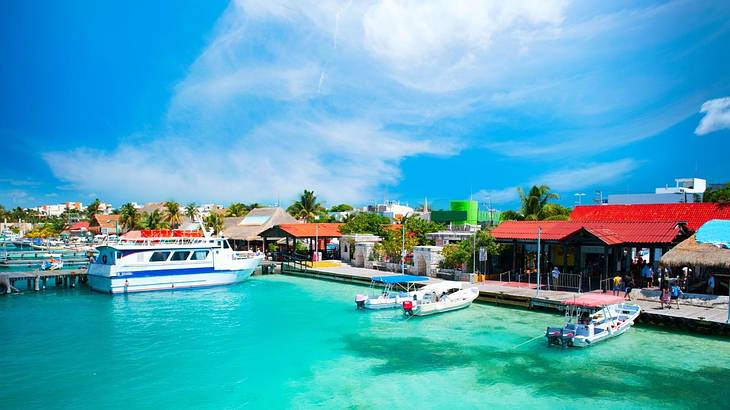 Turquoise water with boats on it and small buildings with red roofs behind them