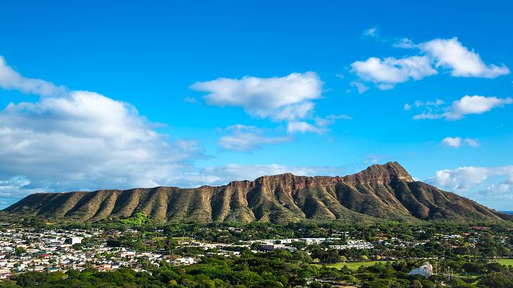 Aerial view of a volcano with buildings and tropical trees at its feet