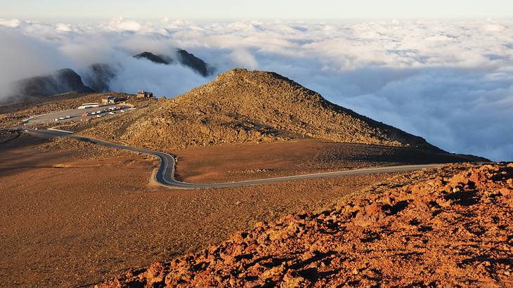 A road on top of a mountain leading to an observation area overlooking clouds