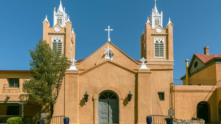 An adobe church with two spires under a clear blue sky