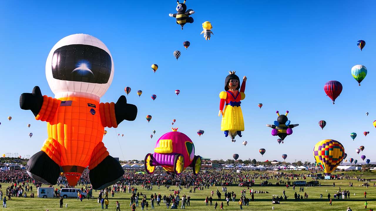 Big colorful hot air balloons in the air on a sunny day above green grass