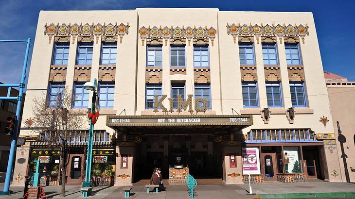 The front of a cream colored theater building with a sign that says "KIMO"