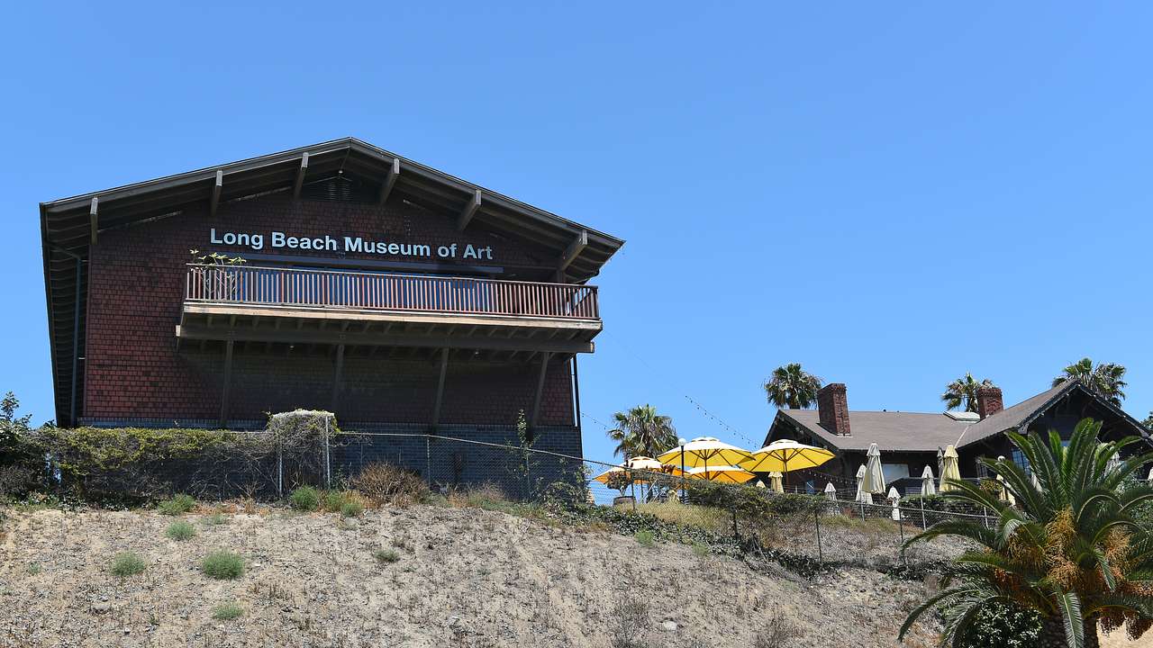 A brick house atop a hill with a "Long Beach Museum of Art" sign on it