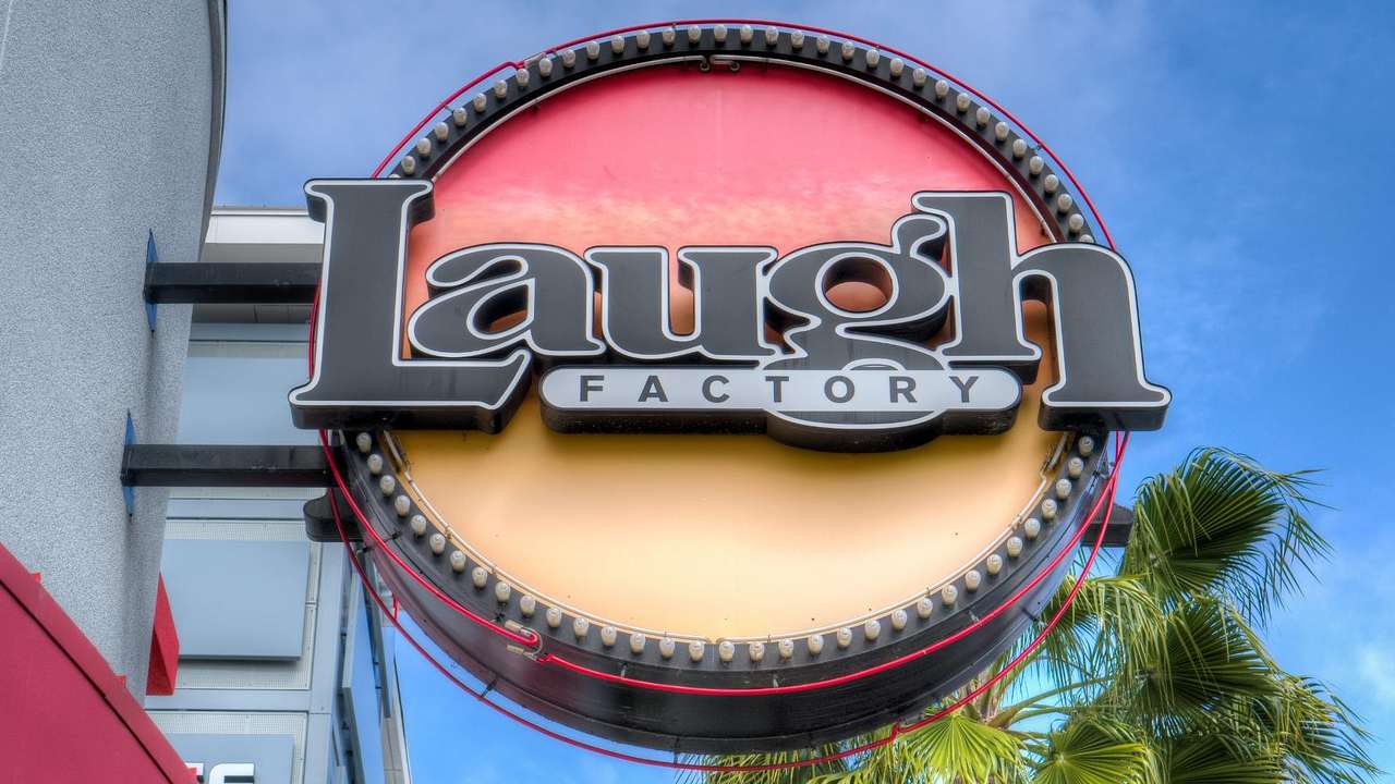 A round sign on a building that says "Laugh Factory"