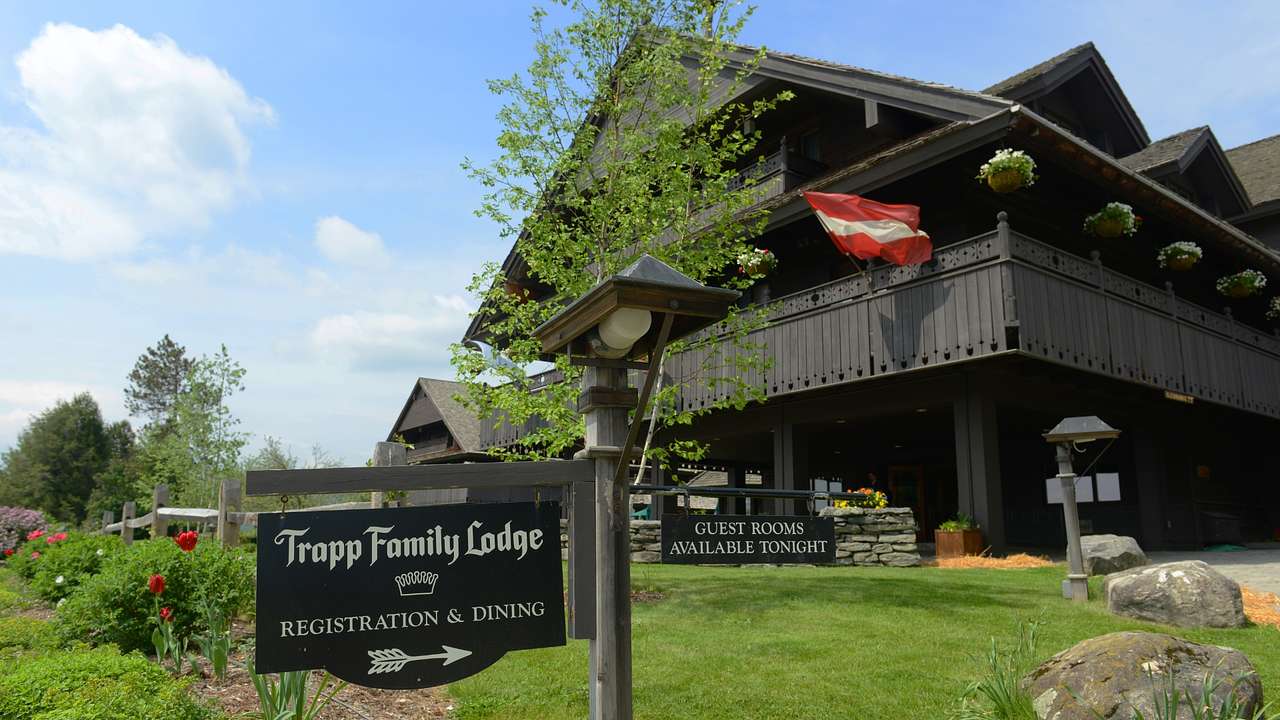 A black wooden ski lodge with an Austrian flag and a "Trapp Family Lodge" sign