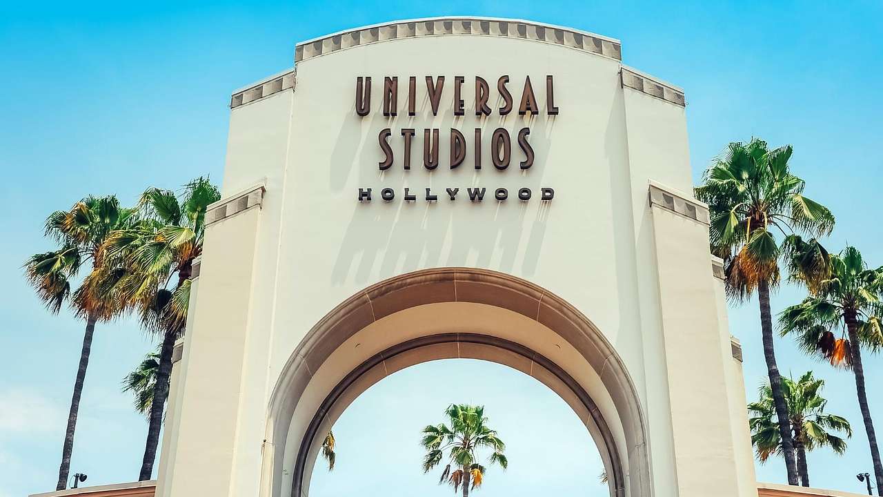 A white arch with a "Universal Studios Hollywood" sign and palm trees next to it