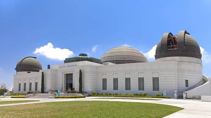 A white building with domed roofs and grass and a path in front of it