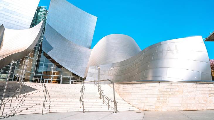 A modern silver structure with steps leading up to it under a clear blue sky