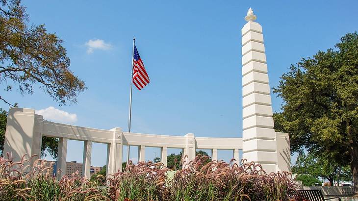 A stone monument and an American flag with a garden surrounding it