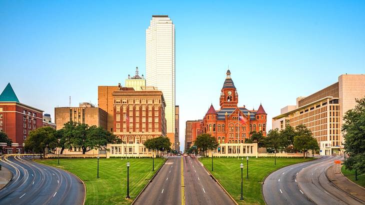 Redbrick buildings and a skyscraper with roads and grass in front