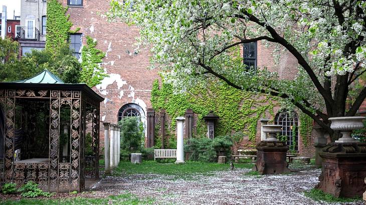 A tranquil garden with sculptures and a big red brick building at the back