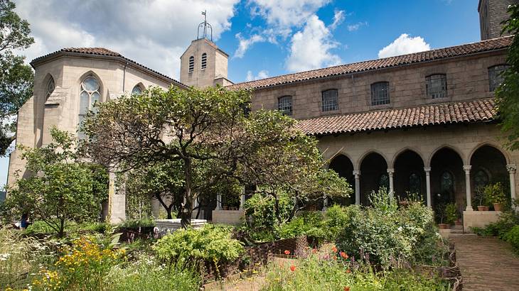 A romanesque-style building next to a lush green garden