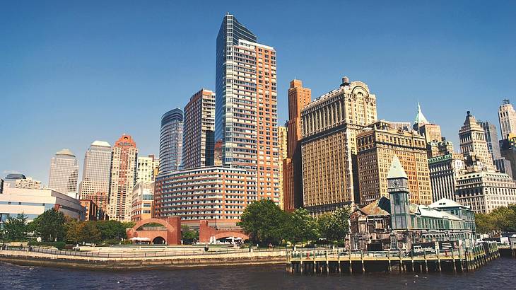 Buildings on the shore with a river in front of them under a blue sky