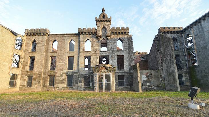 The ruins of a hospital next to grass under a blue sky with some cloud