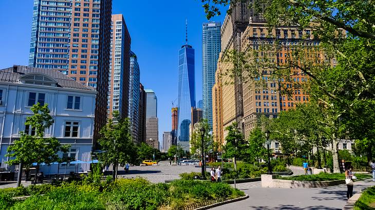 An urban park with trees and a walking path, and a skyline in the background