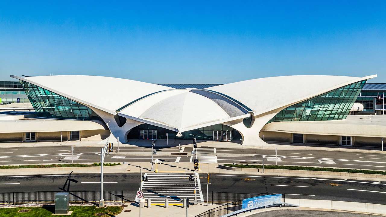 A modern white airport terminal with roads in front of it