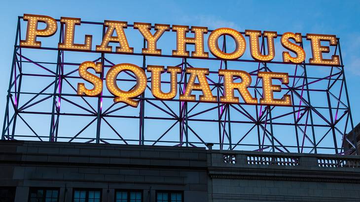 A sign that says "Playhouse Square" on a building at dusk