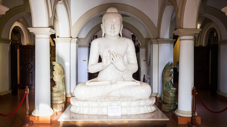 A white Buddha statue surrounded by white arched pillars