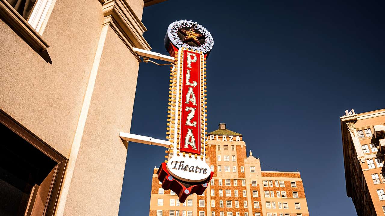 A sign that says "Plaza Theater" next to a building and a dark blue sky