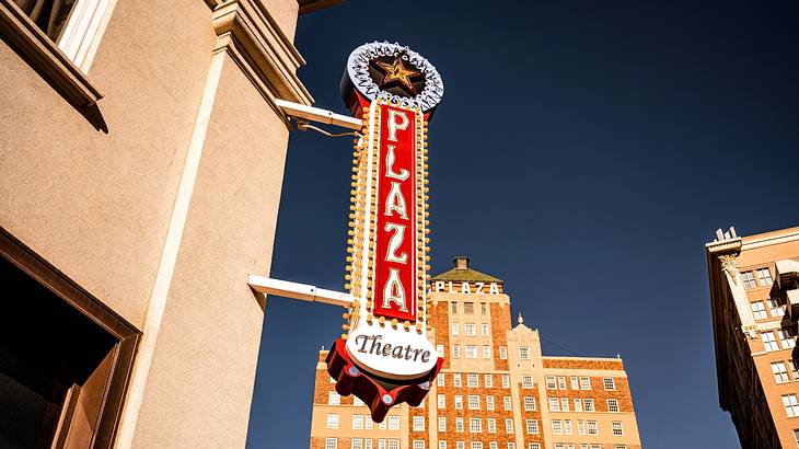 A sign that says "Plaza Theater" next to a building and a dark blue sky