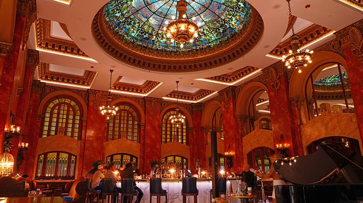 A bar with pink marble walls, arched windows, and a glass dome with a chandelier