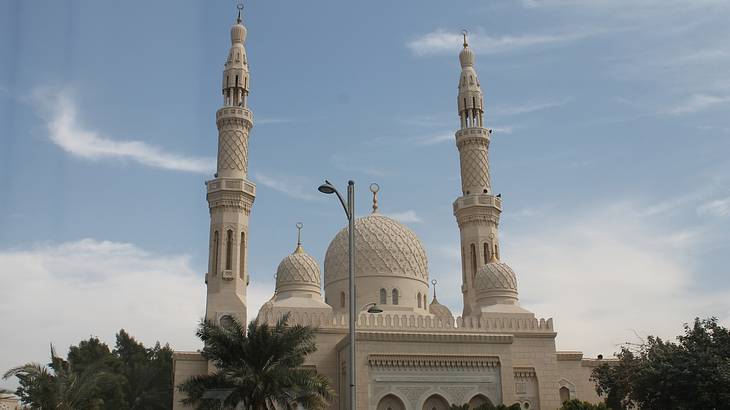 A traditional mosque with two towers and a white stone exterior on a sunny day