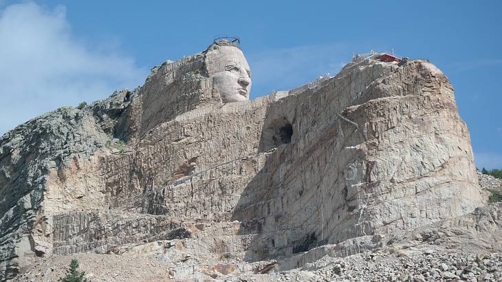 A rock cliff with the face of a man carved into it under a blue sky