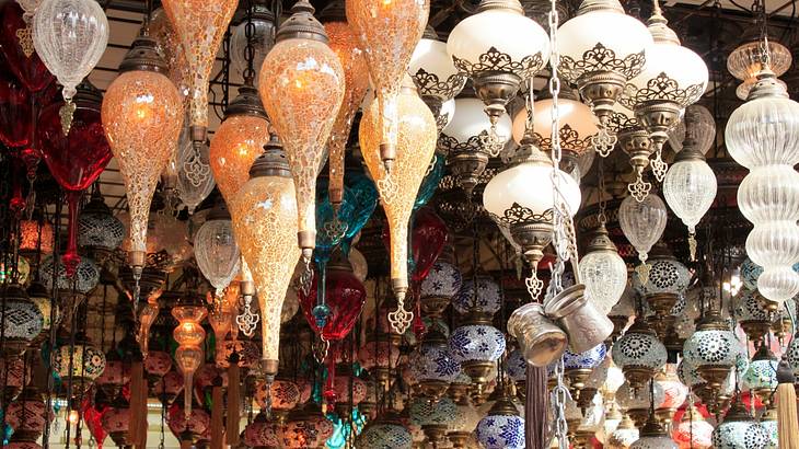 Colorful ceramic artifacts and glass lamps hanging from a market stall ceiling