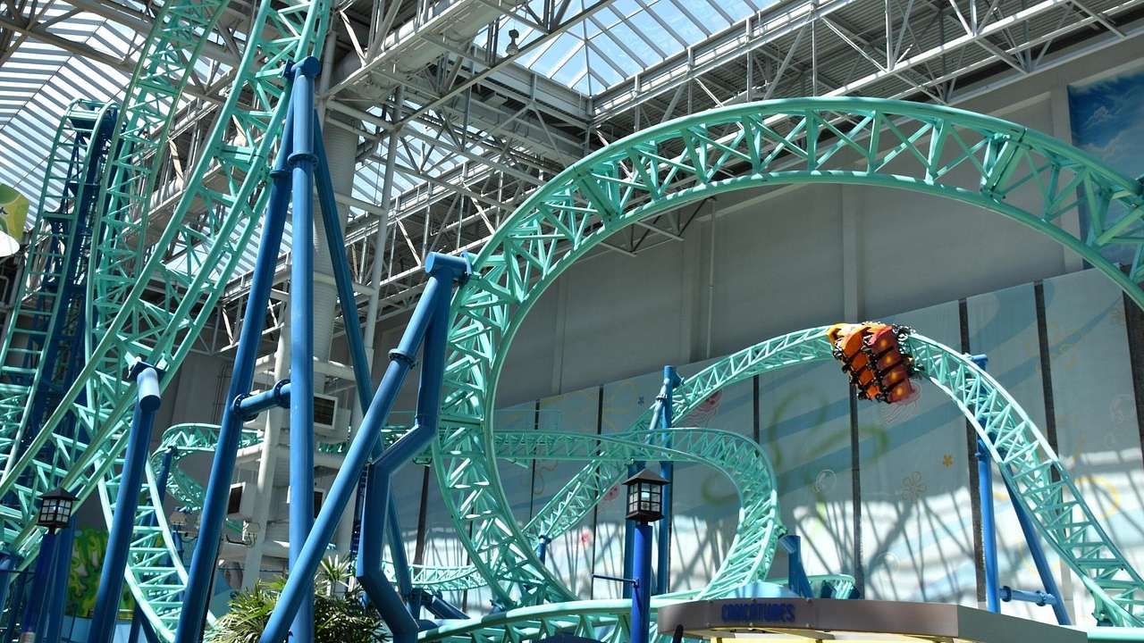 A cyan roller coaster inside an indoor amusement park