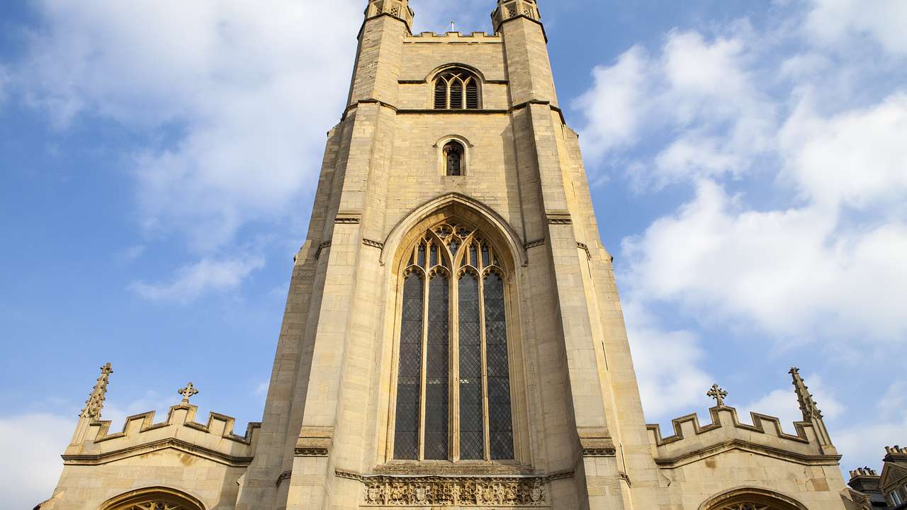 A tall stone church tower with a large arched window and two small ones