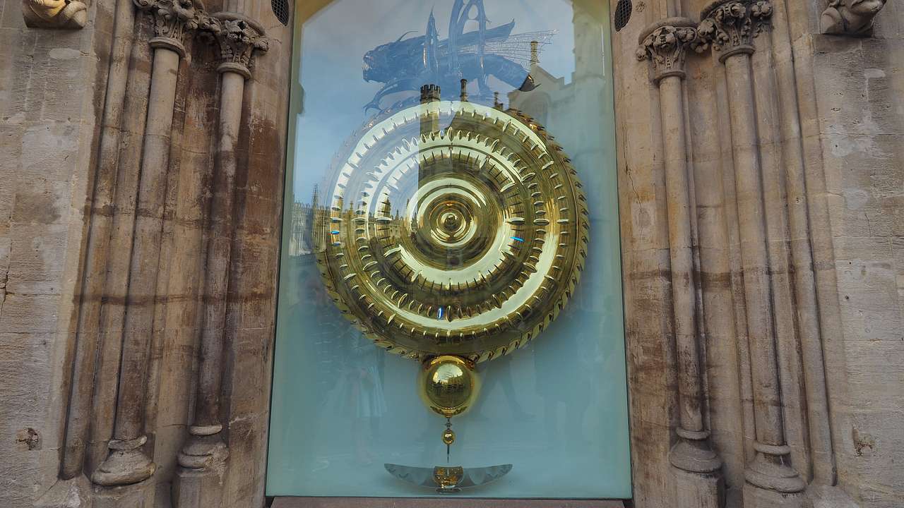 A huge gold clock with no hands and a black grasshopper on top inside a glass casing