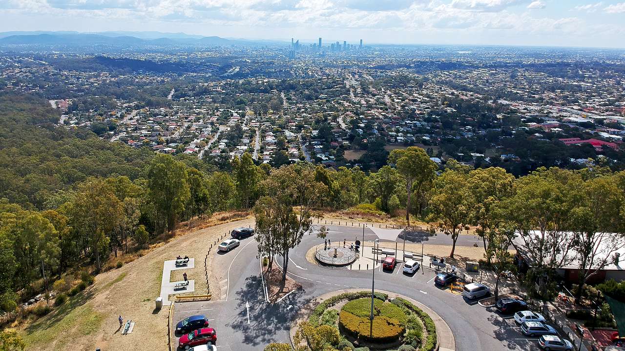 Aerial of a city skyline from a faraway mountaintop lookout with parked cars