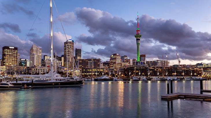 A harbour at sunset with a beautiful yacht and lit up city buildings at the back A harbour at sunset with a beautiful yacht and lit up city buildings at the back