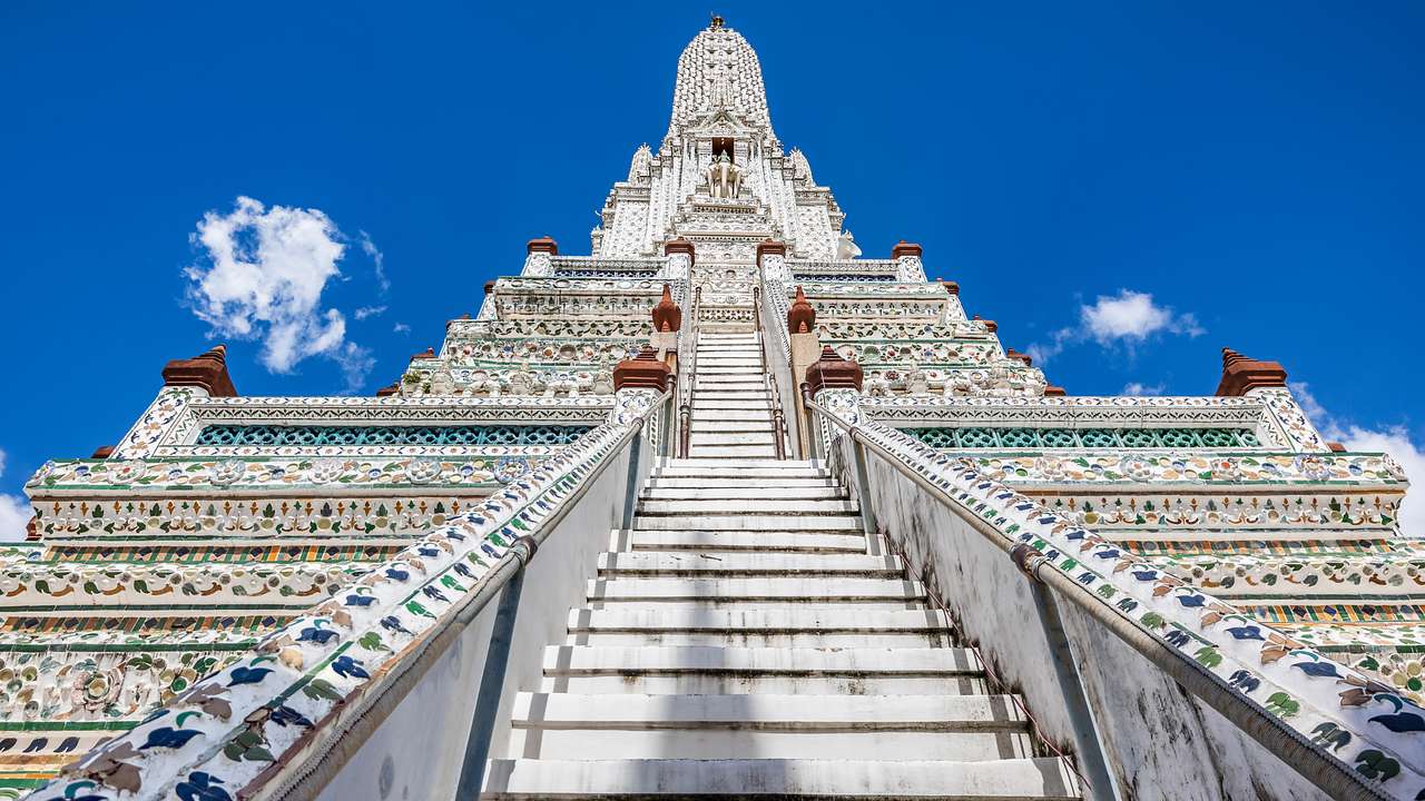 View of a white temple with a staircase covered in carvings from below