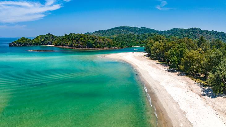 An island from above with blue sky and water and green rainforest