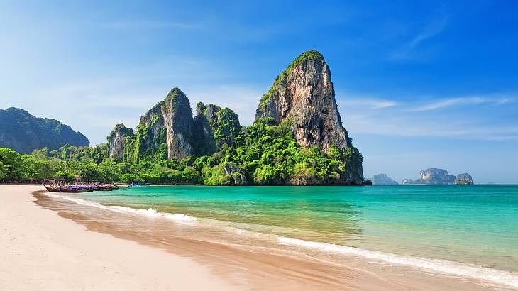 Side-angle view of a beach with limestone cliffs and greenery along its coast