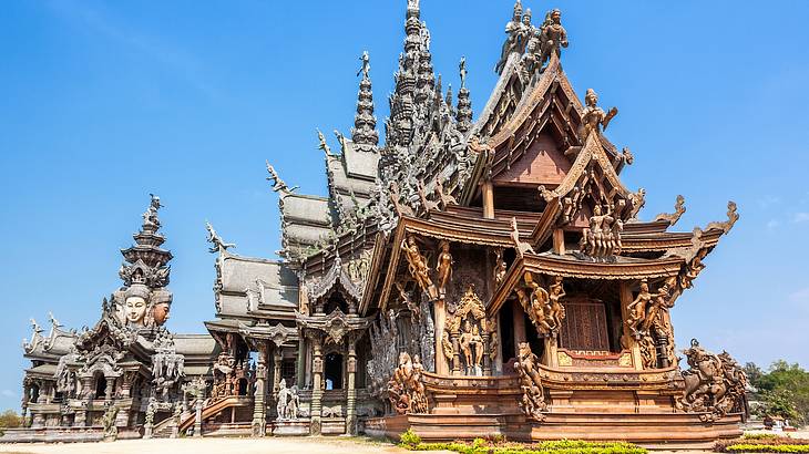 The exterior view of a temple covered in detailed Buddhist carvings, against blue sky